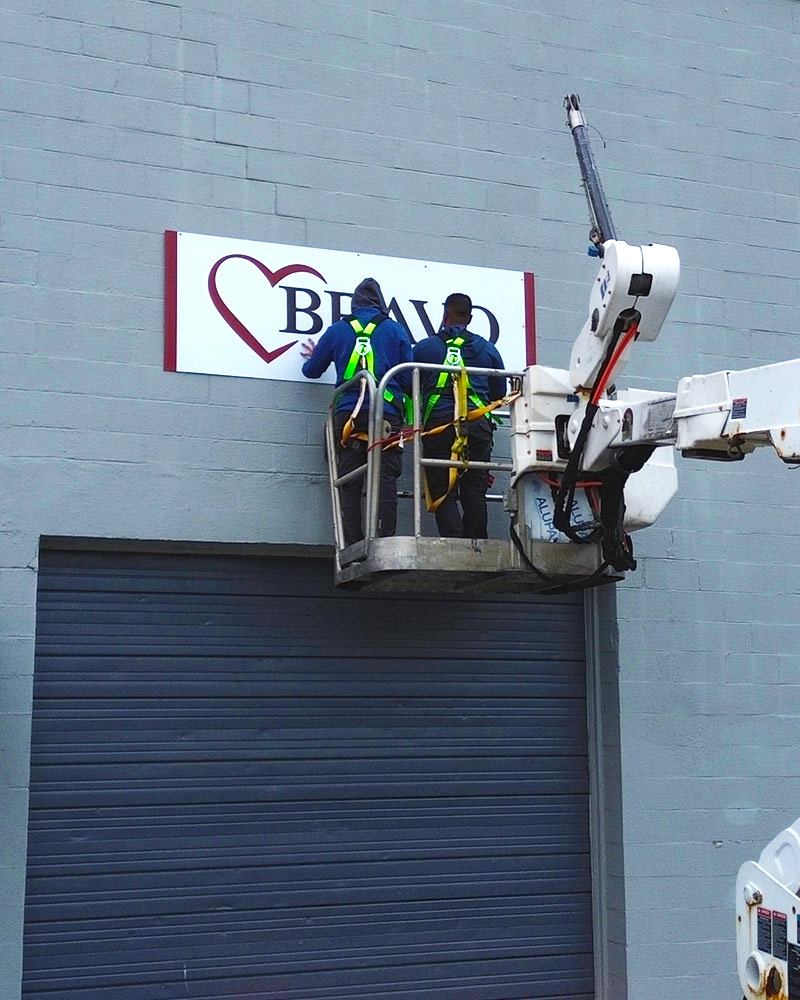 Two Iconic Signs & Graphics installers putting up a custom sign